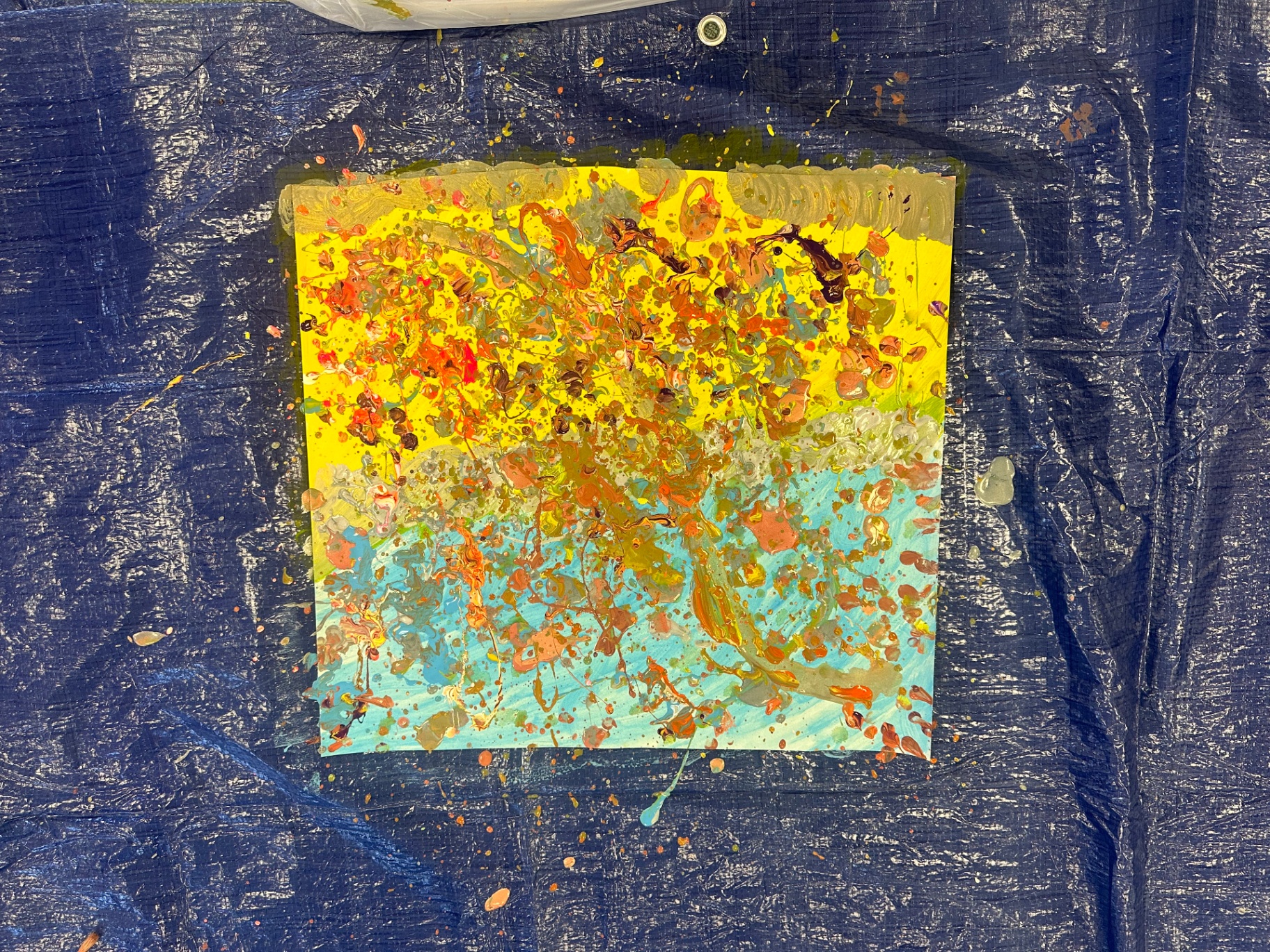 A child's vivid splatter painting in yellow, blue, orange and brown